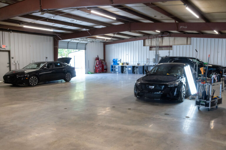 The main work bay at Heartland Dent Shop in Tulsa with vehicles under painless dent repair lighting.