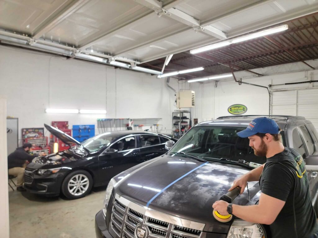 Multi-step paint correction in progress- Heartland Dent Shop - Heartland Dent Shop Heartland Dent Shop technician machine-polishing the hood of a dark SUV during paint correction in Tulsa.