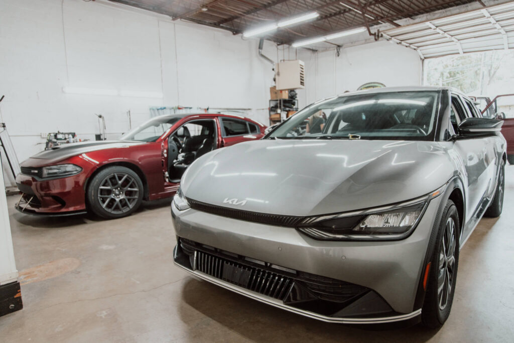 A Kia EV6 and Dodge Charger in the work bay at Heartland Dent Shop in Tulsa.